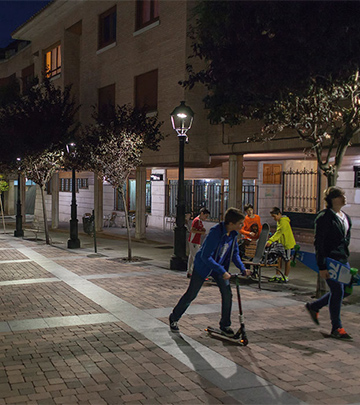 Ludzie spacerujący nocą po ulicach miasta Palencia w promieniach oświetlenia Philips