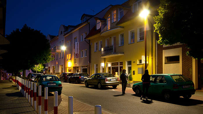 Ludzie spacerujący nocą po ulicach miasta w promieniach oświetlenia ulicznego Philips 