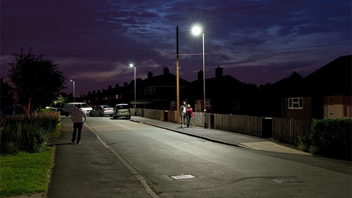 Ludzie spacerujący po ulicy oświetlonej lampami Philips