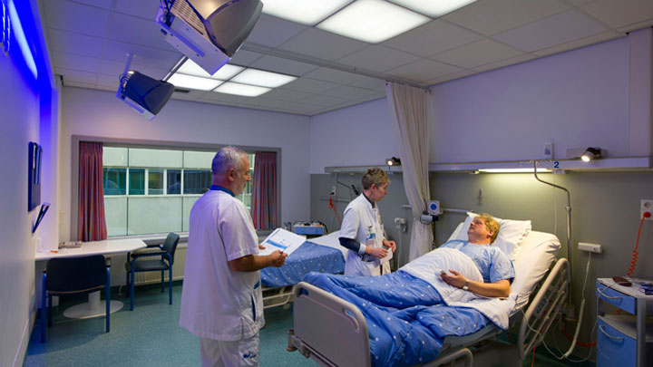 Lekarze zajmujący się pacjentem w gabinecie oświetlonym za pomocą systemu Philips Healwell