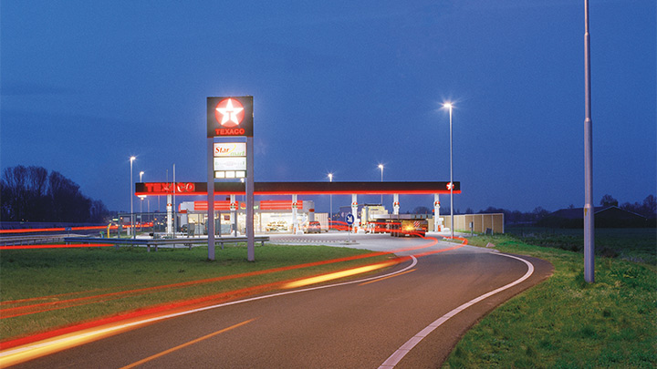 Atrakcyjnie oświetlona po zmroku stacja paliw Texaco przy autostradzie — przyciągające wzrok oświetlenie zewnętrzne