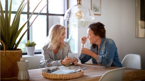 Dwie kobiety rozmawiające we wnętrzu, w którym zamontowana jest lampa z żarówką Philips