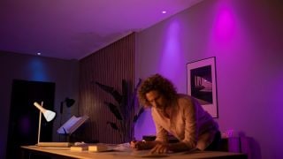 Inteligentne żarówki Philips Hue tworzą w salonie nastrojowe światło w odcieniach fioletu i różu, które można dostosować do atmosfery, idealne na wieczory filmowe i relaks w nowoczesnym domu.
