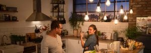 „Nowoczesna kuchnia z lampami wiszącymi LED w stylu vintage, oświetlającymi dwie kobiety przy kolacji, tworząc ciepłą, przytulną atmosferę.”