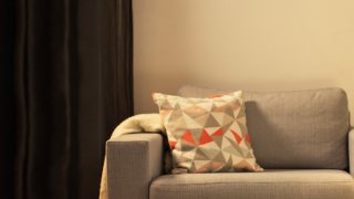 „Przytulny salon z nowoczesną lampą stołową LED, oświetlającą szarą sofę dwuosobową i tworzącą ciepłą atmosferę do relaksu w domu”.