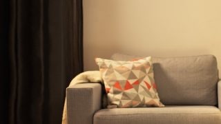 Przytulny salon z nowoczesną lampą stołową LED, oświetlającą szarą sofę dwuosobową i tworzącą ciepłą atmosferę sprzyjającą domowemu relaksowi.